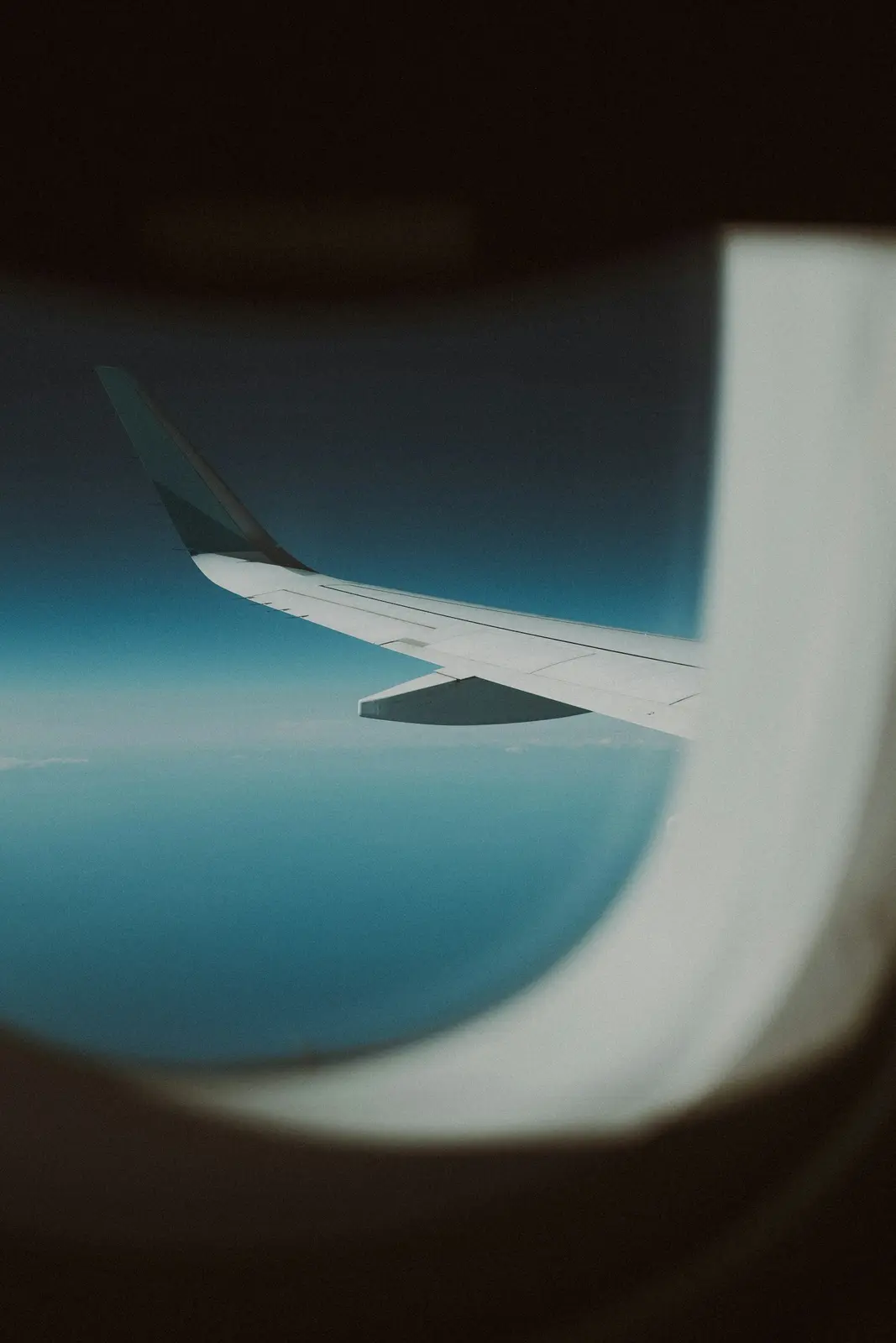 Airplane wing above the clouds seen from a window seat